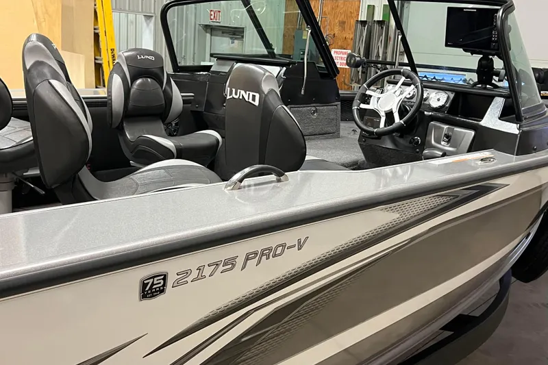 Slide: The Image of 2023 Lund 2175 Pro-V boat interior with steering wheel and seating. - 58