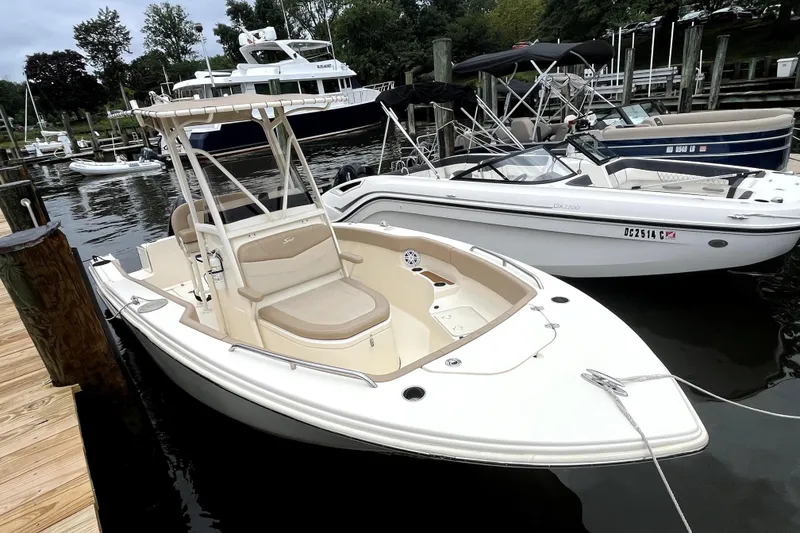 Slide: The Image of 2023 Scout 215 XSF boat docked at marina, featuring sleek design and spacious seating. - 2