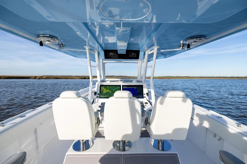 Slide: The Image of 2024 Invincible 40 Catamaran interior with navigation screens, white seating, and blue canopy on water. - 27