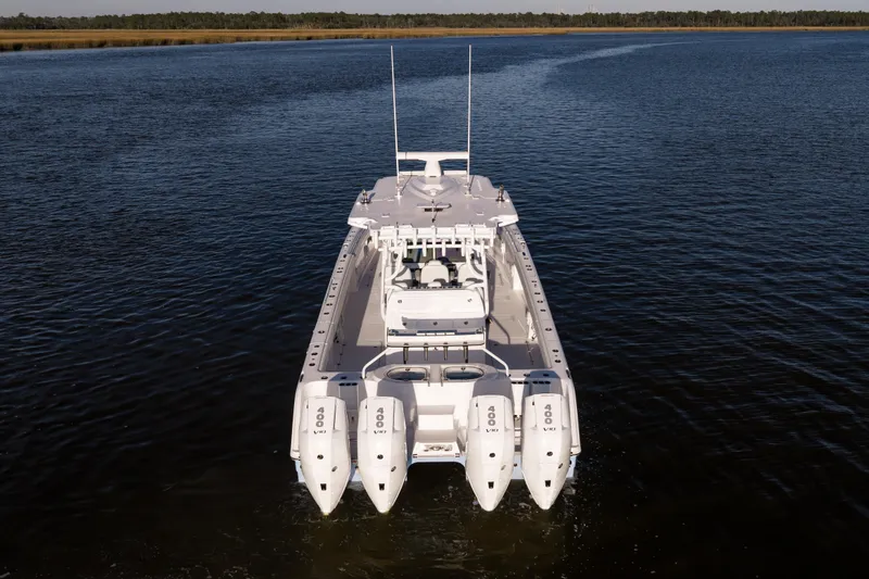 Slide: The Image of 2024 Invincible 40 Catamaran on calm water, rear view with four engines. - 3