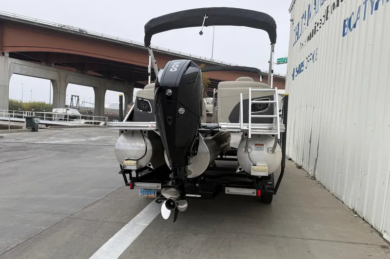 Slide: The Image of 2020 Bennington 22 SSRFBXP pontoon boat with outboard motor, parked near a bridge. - 2