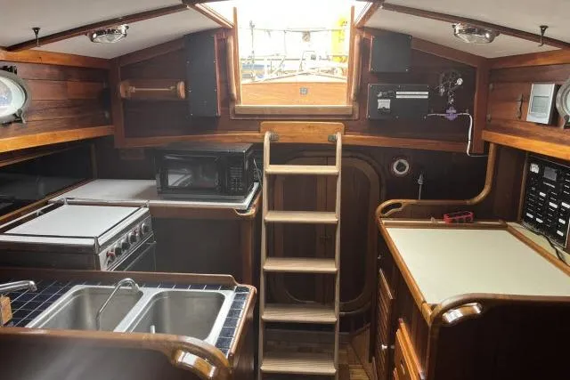 Slide: The Image of Interior of a 1977 Alajuela A38 sailboat with wooden cabinetry and kitchen amenities. - 18