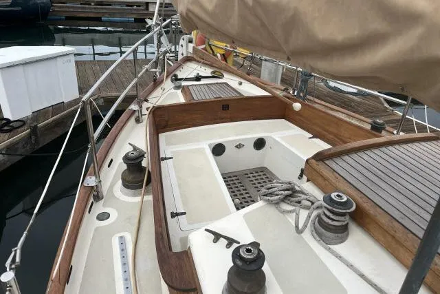 Slide: The Image of 1977 Alajuela A38 sailboat deck with wooden trim and winches at a marina. - 19