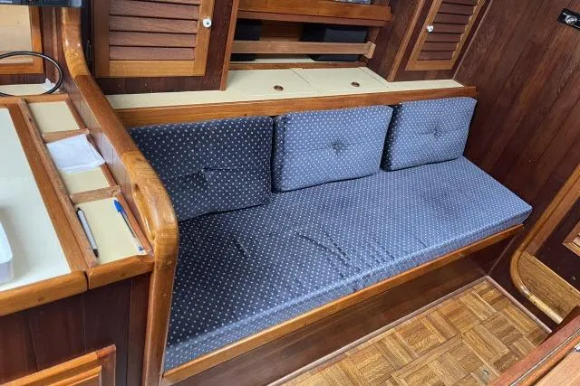 Slide: The Image of Interior of 1977 Alajuela A38 sailboat with blue cushioned seating and wooden cabinetry. - 2