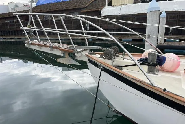 Slide: The Image of 1977 Alajuela A38 sailboat docked, featuring a wooden deck and metal railings. - 31