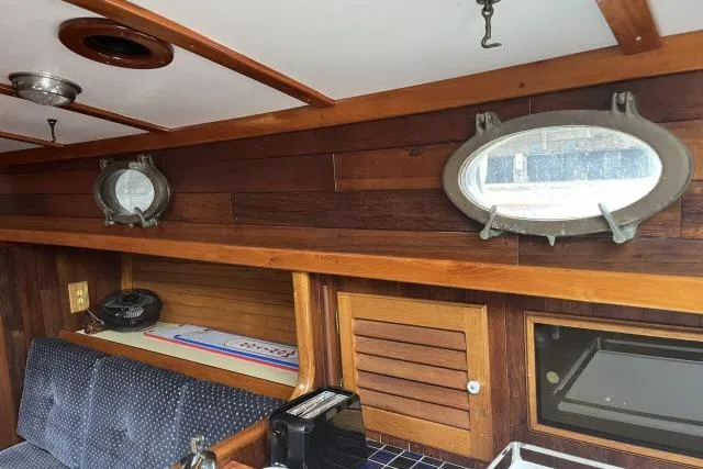 Slide: The Image of Interior of a 1977 Alajuela A38 sailboat with wooden paneling and porthole windows. - 4