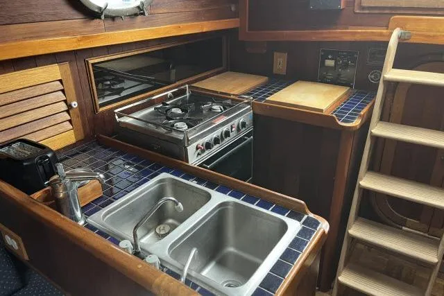 Slide: The Image of 1977 Alajuela A38 yacht kitchen with dual sinks, stove, and wooden cabinetry. - 5