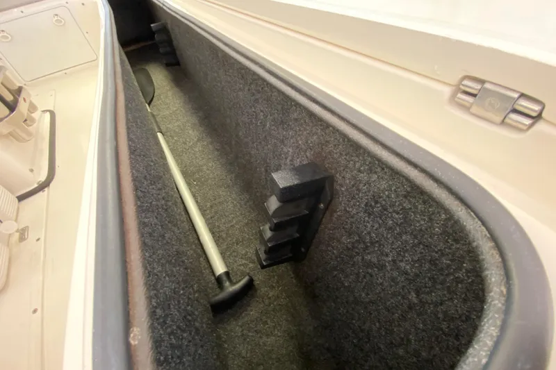 Slide: The Image of Storage compartment in a 2008 Famous Craft 18 boat, featuring a paddle and carpet lining. - 34