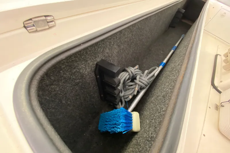 Slide: The Image of Storage compartment in a 2008 Famous Craft 18 boat with cleaning brush and rope. - 36