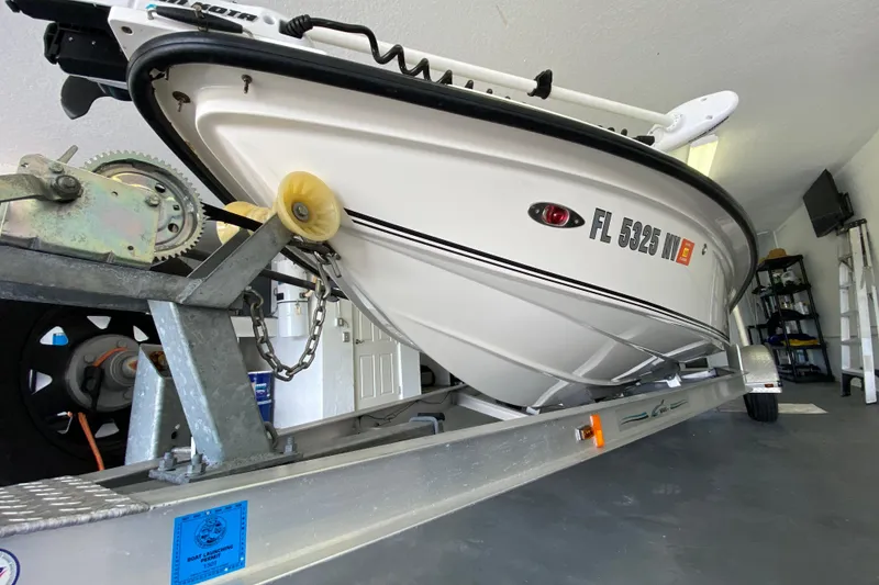 Slide: The Image of White 2008 Famous Craft 18 boat on trailer in garage, registration FL 5325 NW visible. - 8