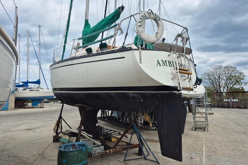 Slide: The Image of 1978 Hunter 30 sailboat on dry dock, with green sails and "Ambitious" name visible. - 18