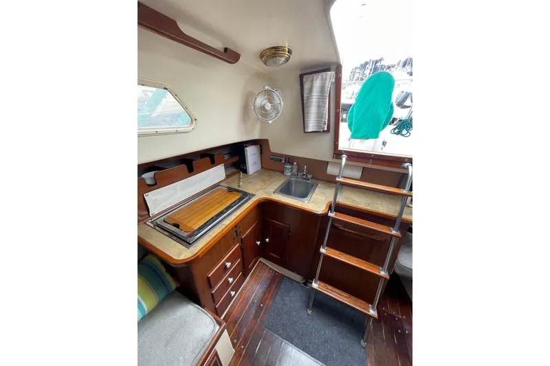 Slide: The Image of 1978 Hunter 30 yacht interior with wooden cabinetry, compact kitchen, and ladder access. - 27