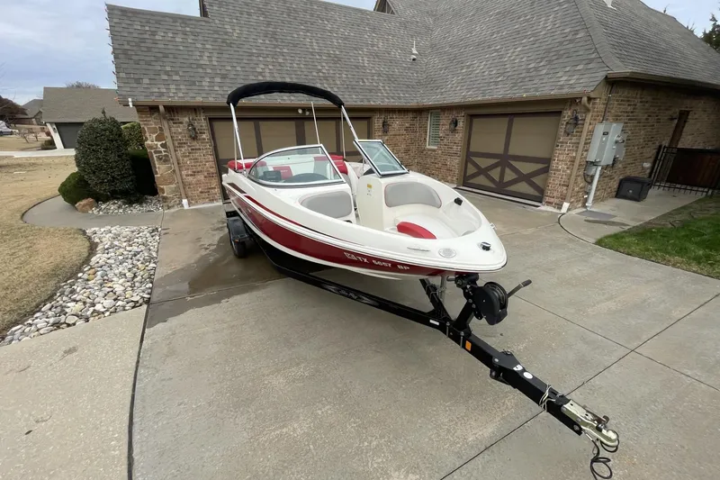 Slide: The Image of 2011 Sea Ray 175 Sport boat on trailer in driveway, red and white design. - 3