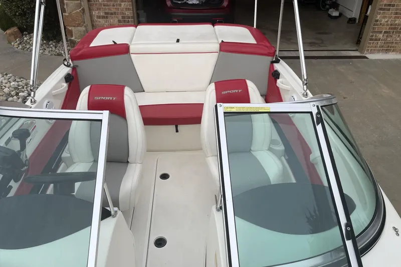 Slide: The Image of 2011 Sea Ray 175 Sport boat interior with red and white seating, parked in driveway. - 6