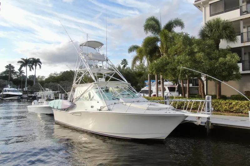 Slide: The Image of 2001 Cabo 35 Express yacht docked by palm trees and waterfront buildings. - 12