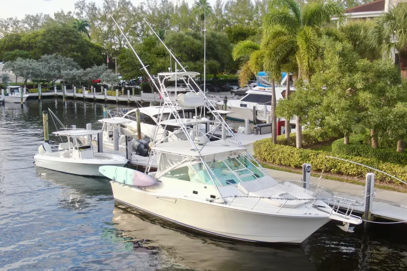 Slide: The Image of 2001 Cabo 35 Express boat docked in a scenic marina with lush greenery. - 13