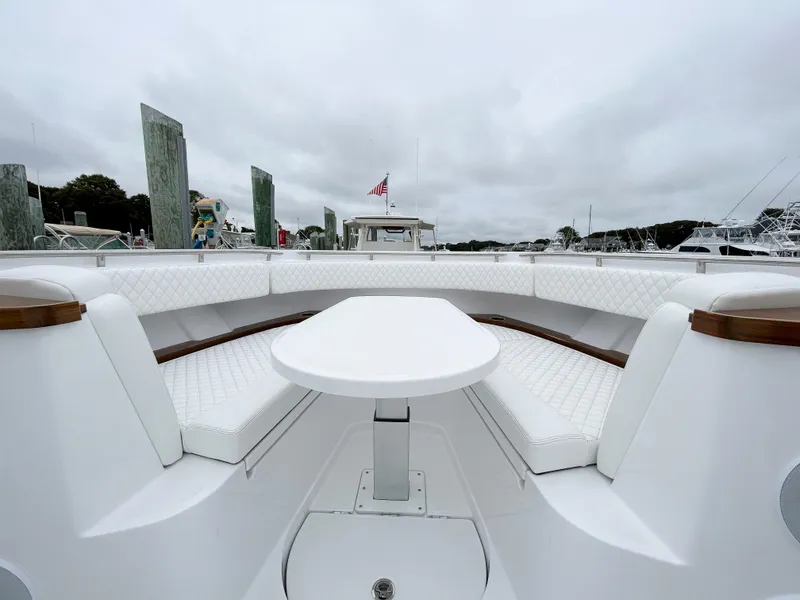Slide: The Image of 2025 HCB 48 Campeon boat interior with white seating and table, docked at marina. - 15
