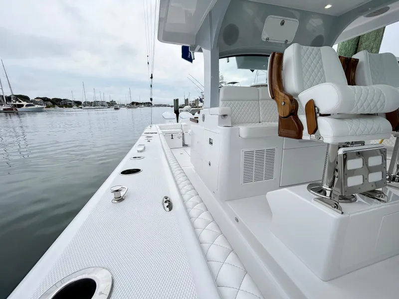 Slide: The Image of 2025 HCB 48 Campeon luxury boat with plush seating, docked in a serene marina. - 42