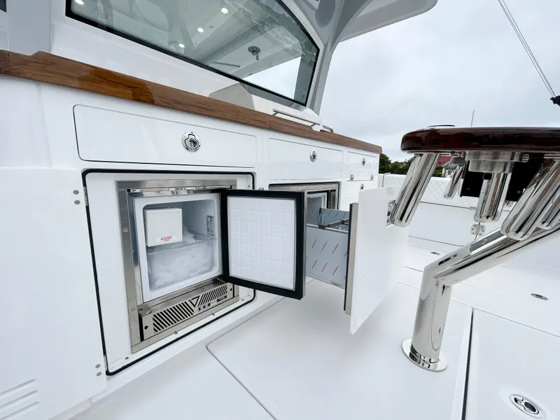 Slide: The Image of 2025 HCB 48 Campeon boat interior with open fridge and storage compartments. - 44