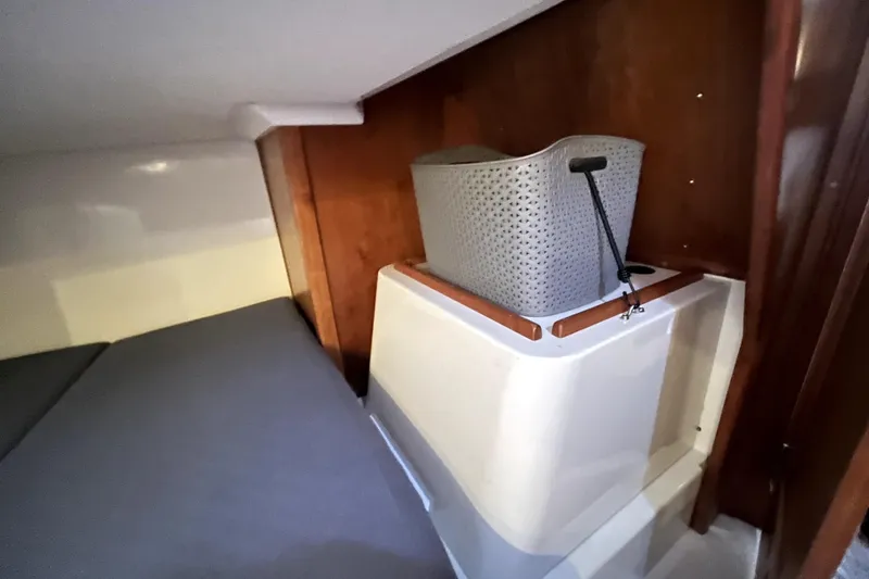 Slide: The Image of Small cabin interior with a gray basket, wooden paneling, and a cushioned seat in a 2005 C&C 110. - 14