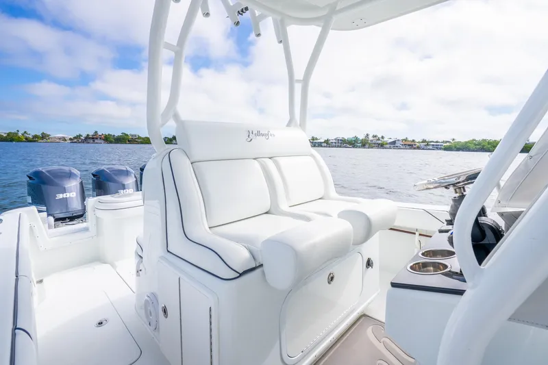 Slide: The Image of 2016 Yellowfin 36 Offshore boat interior with white seating and dual engines on a sunny day. - 23