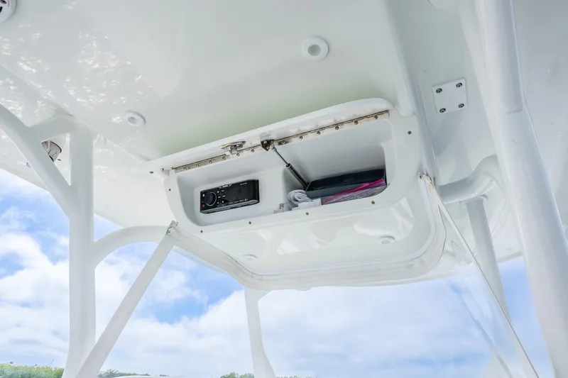 Slide: The Image of 2016 Yellowfin 36 Offshore boat storage compartment with electronic equipment, under a clear blue sky. - 24