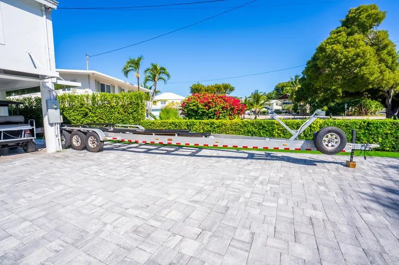 Slide: The Image of Trailer for 2016 Yellowfin 36 Offshore boat on paved driveway, surrounded by greenery. - 56