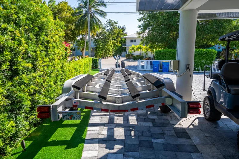 Slide: The Image of Boat trailer parked in driveway, surrounded by lush greenery and palm trees. - 57