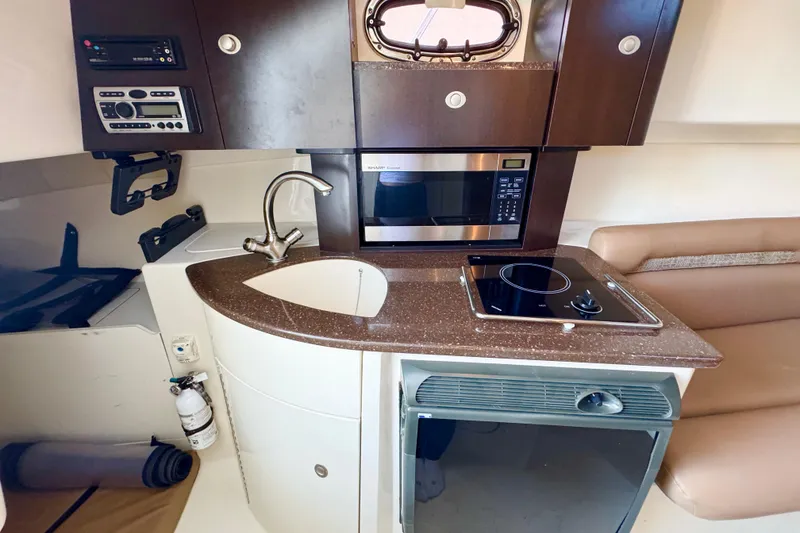 Slide: The Image of 2006 Boston Whaler 285 Conquest boat interior with kitchenette, sink, microwave, and stove. - 23