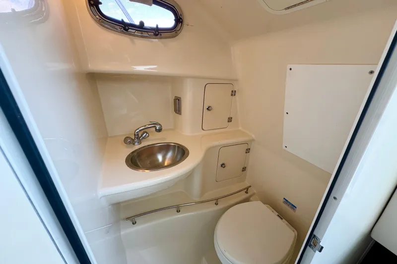 Slide: The Image of 2006 Boston Whaler 285 Conquest boat bathroom with sink, toilet, and storage cabinets. - 29