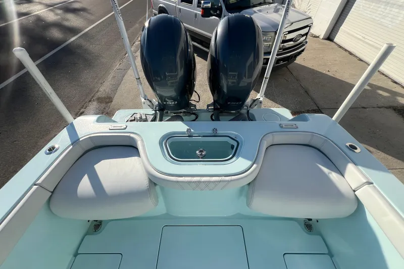 Slide: The Image of 2024 Contender 24 Sport boat with dual engines and seating, parked near a road. - 10