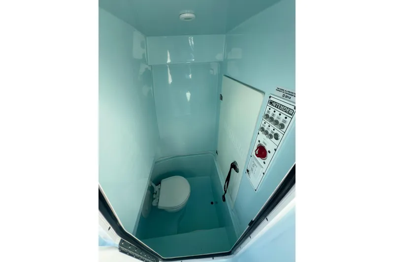 Slide: The Image of 2024 Contender 24 Sport boat interior with compact marine toilet and control panel. - 6