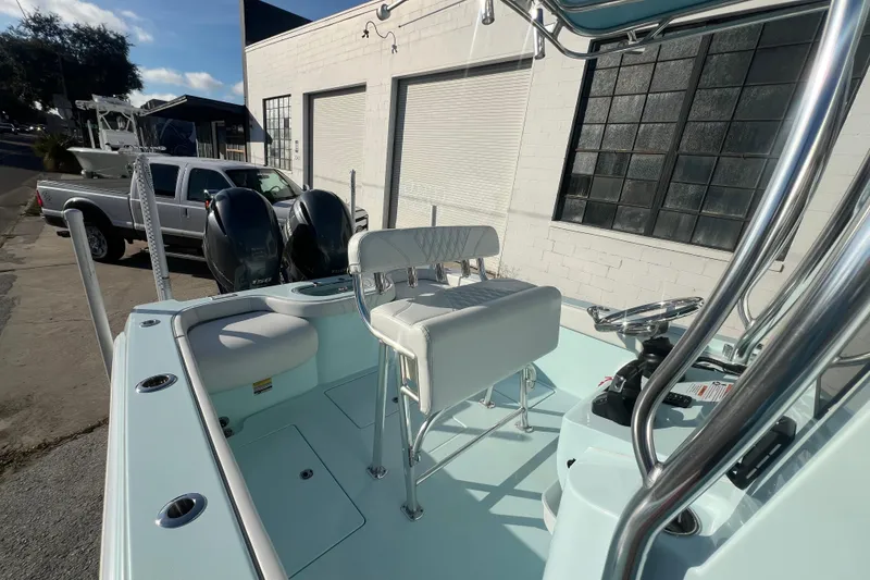 Slide: The Image of 2024 Contender 24 Sport boat with dual engines, parked near a white building. - 8