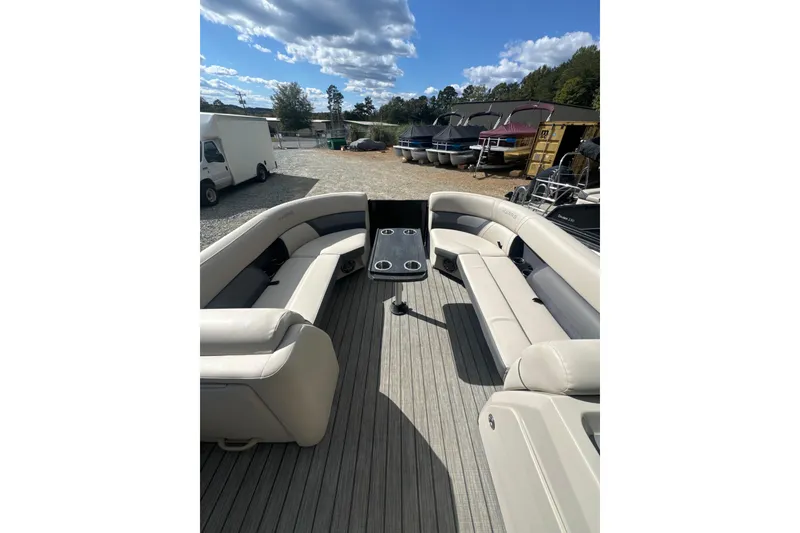 Slide: The Image of 2023 Harris HCX 230 Swingback boat interior with seating and table under a blue sky. - 15