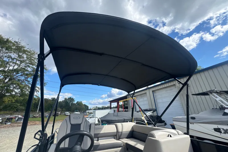 Slide: The Image of 2023 Harris HCX 230 Swingback boat with canopy, parked outdoors under a cloudy sky. - 20