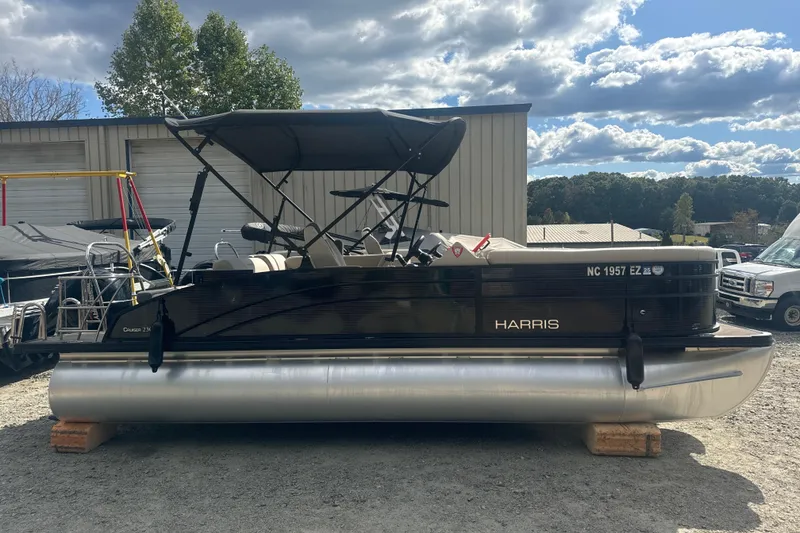 Slide: The Image of 2023 Harris HCX 230 Swingback pontoon boat with canopy, parked outdoors under cloudy sky. - 22