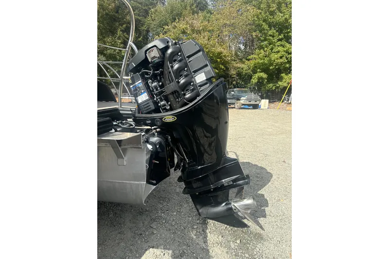 Slide: The Image of 2023 Harris HCX 230 Swingback boat motor, black, parked on gravel with trees in background. - 27