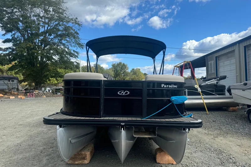 Slide: The Image of 2023 Harris HCX 230 Swingback pontoon boat on display outdoors, under a blue sky. - 5