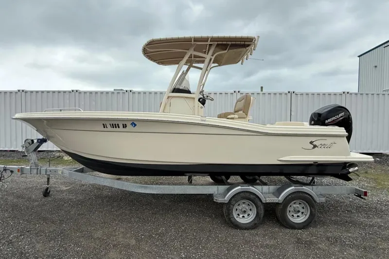 The Image of 2023 Scout 215 XSF boat on trailer, side view, overcast sky. - 1