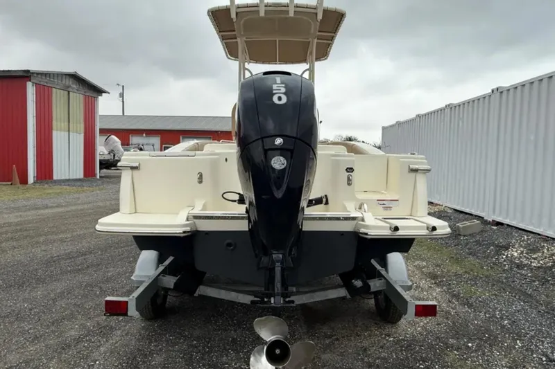 Slide: The Image of 2023 Scout 215 XSF boat with outboard motor on trailer, parked outdoors. - 6