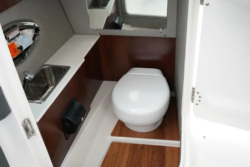 Slide: The Image of 2026 Chaparral 270 OSX boat bathroom with sink, toilet, and mirror. - 19