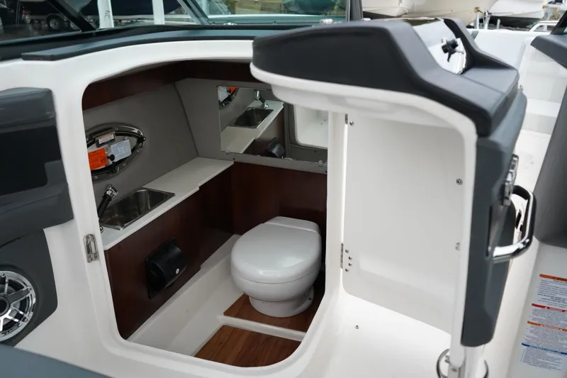 Slide: The Image of Interior of 2026 Chaparral 270 OSX boat featuring a compact bathroom with sink and toilet. - 23