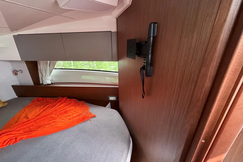 Slide: The Image of Interior cabin of 2026 Beneteau Antares 9 with bed, orange blanket, and wooden paneling. - 23