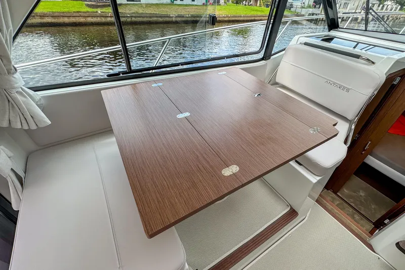 Slide: The Image of Interior of 2026 Beneteau Antares 9 with wooden table and white seating. - 19