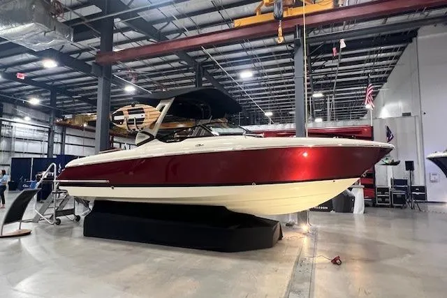The Image of 2026 Chris-Craft Sportster 28 boat displayed indoors, featuring sleek red and white design. - 0