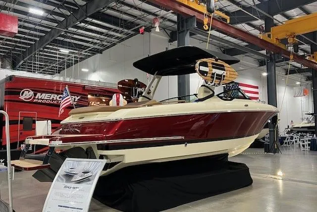 Slide: The Image of 2026 Chris-Craft Sportster 28 boat displayed indoors, featuring a sleek red and cream design. - 1