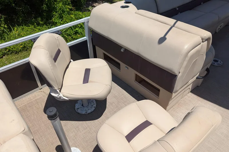 Slide: The Image of 2019 Sun Tracker Fishin' Barge 24 DLX interior with beige seating and storage compartments. - 15