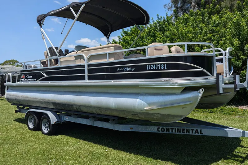 Slide: The Image of 2019 Sun Tracker Fishin' Barge 24 DLX pontoon boat on trailer, parked on grass. - 3