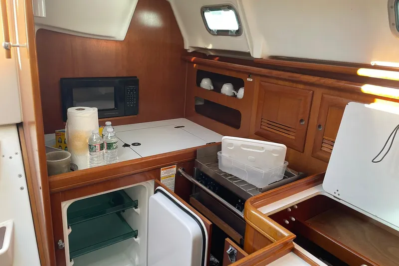 Slide: The Image of Galley of 2000 Beneteau Oceanis 361 sailboat with microwave, fridge, and storage cabinets. - 29
