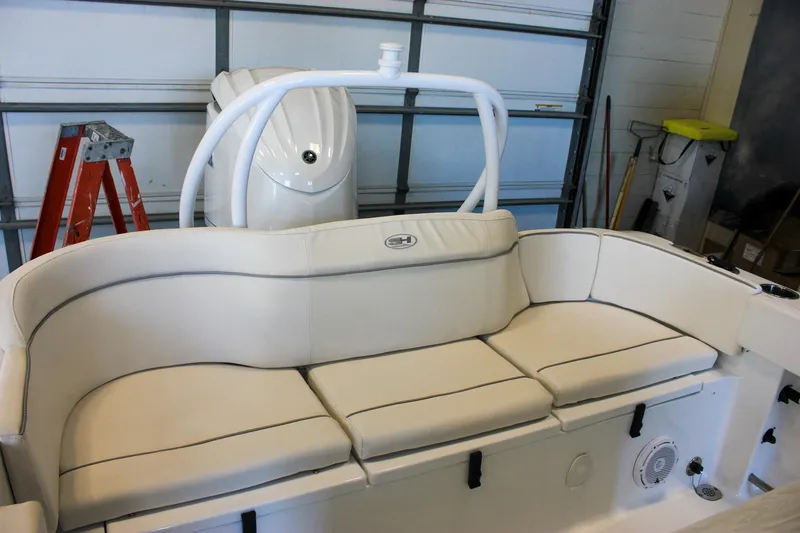 Slide: The Image of 2025 Sea Hunt Ultra 239 SE boat interior with cushioned seating in a garage setting. - 10